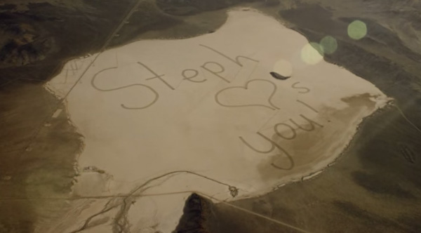 girl draws in sand to end message to astronaut dad