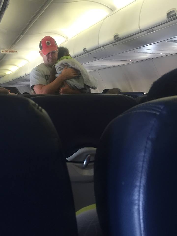 man helps pregnant woman on plane