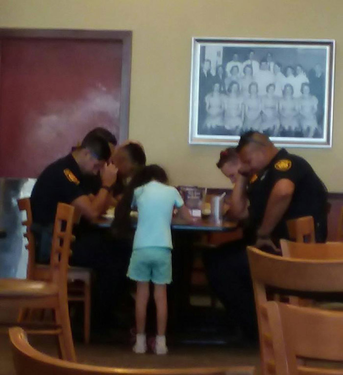 little girl prays with police officers