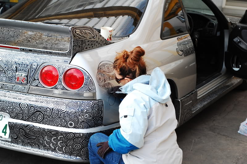 woman draws designs on car with sharpie