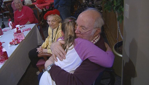 girl gives out hugs to senior citizens