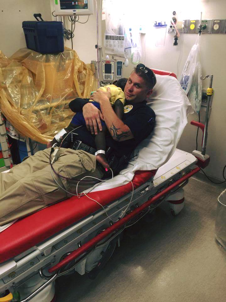 officer cuddles with toddler in hospital