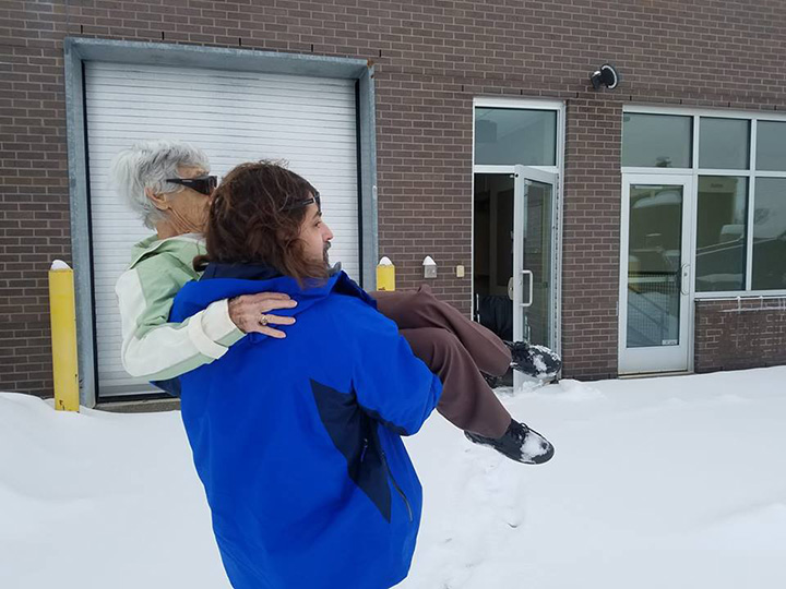 doctor carries elderly patient in the snow