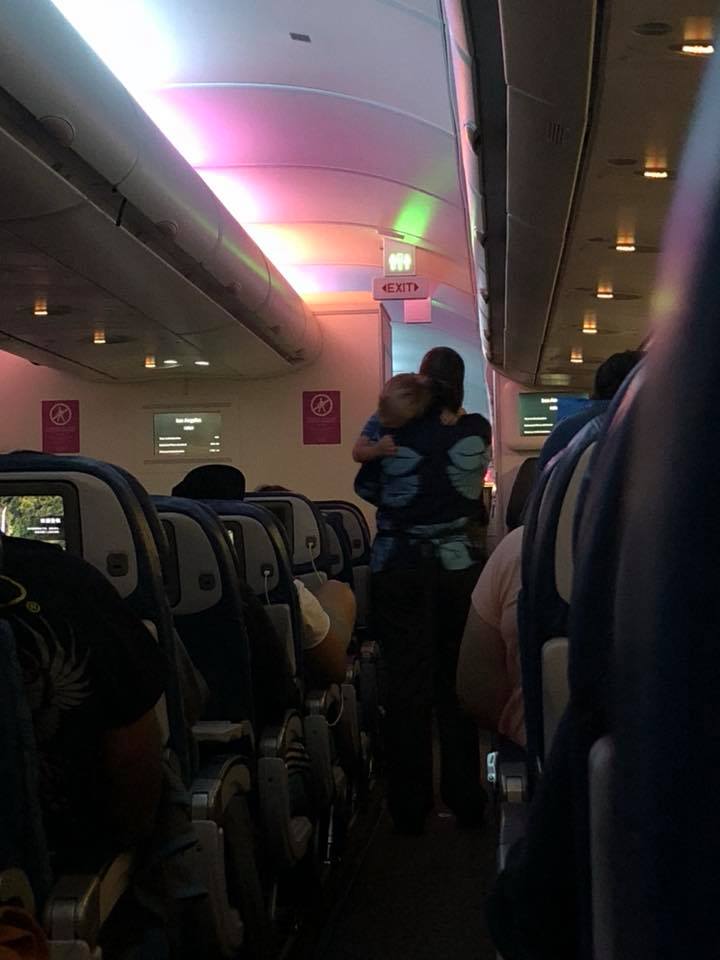 flight attendant calms crying toddler for mom
