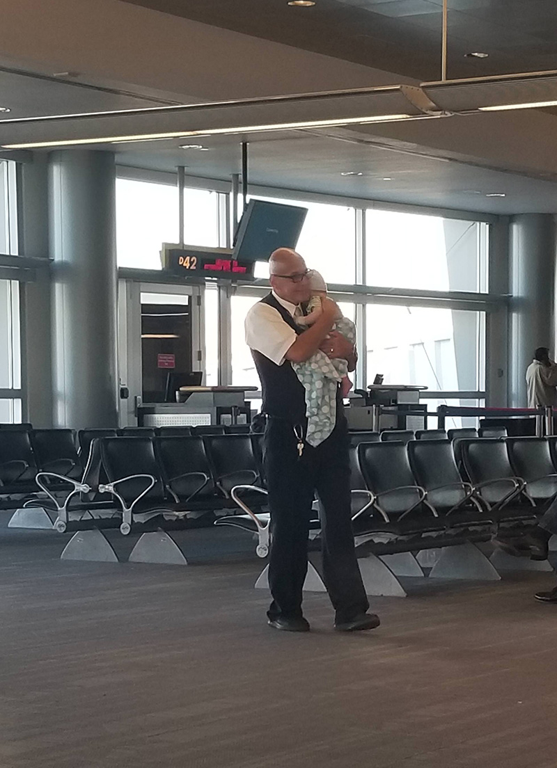 airport employee holds crying baby for mom traveling alone