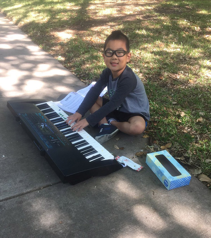 kid plays keyboard outside to raise money for cancer