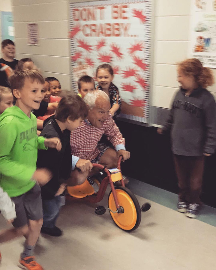 principal challenges kids to read with tricycle push