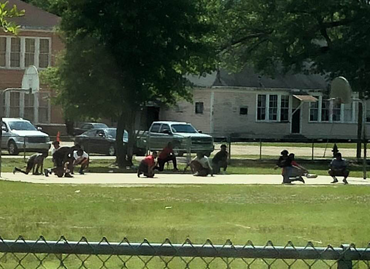 young boys playing basketball kneel for funeral procession