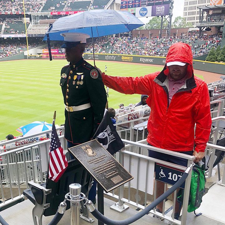 man holds umbrella over military man Braves game