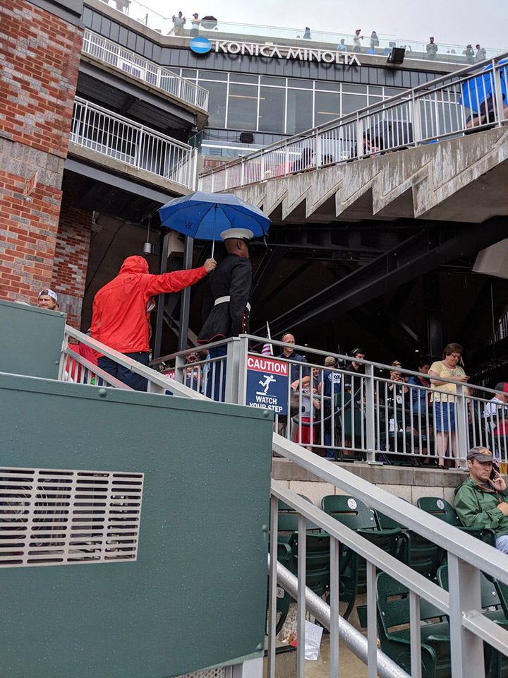man holds umbrella over military man Braves game