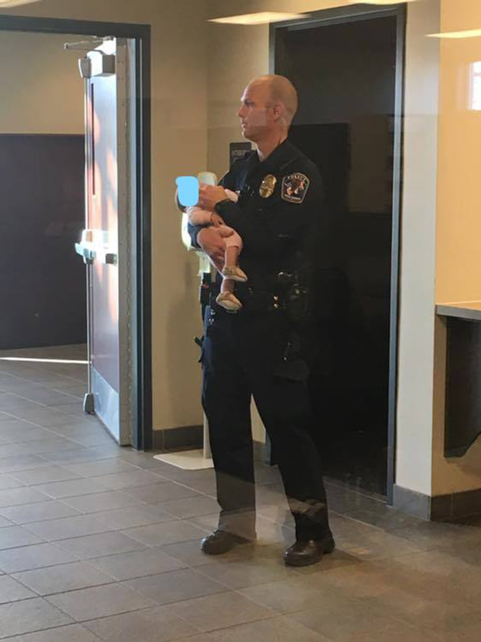 police officer holds baby for mom