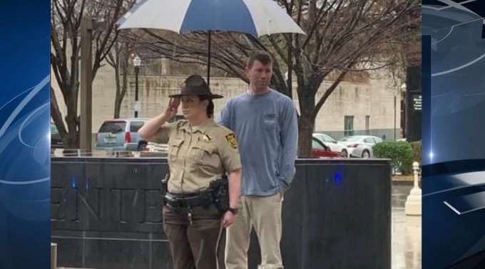 man holds umbrella for officer