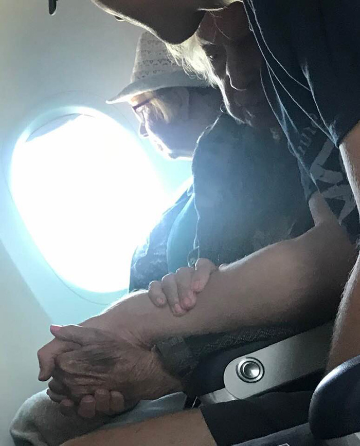 man comforts elderly woman on plane