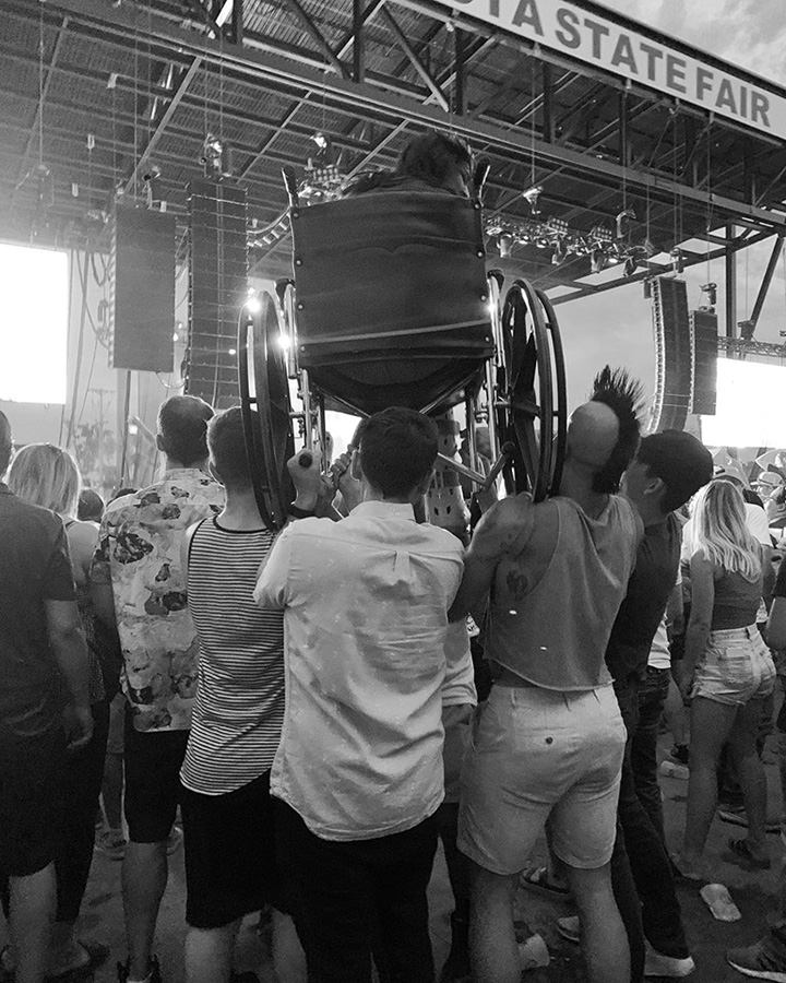 crowd holds up fan in wheelchair at weezer concert