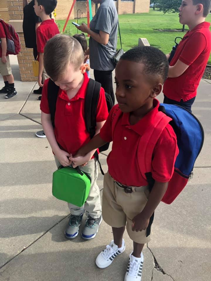 boy holds hand of crying kid first day of school