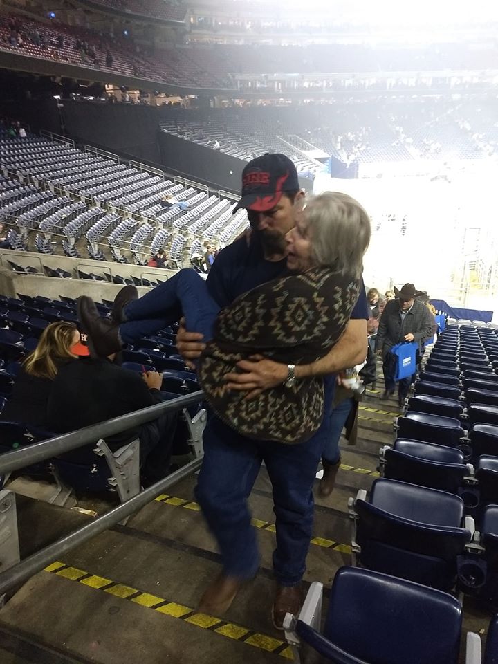 man carries woman to seat in stadium