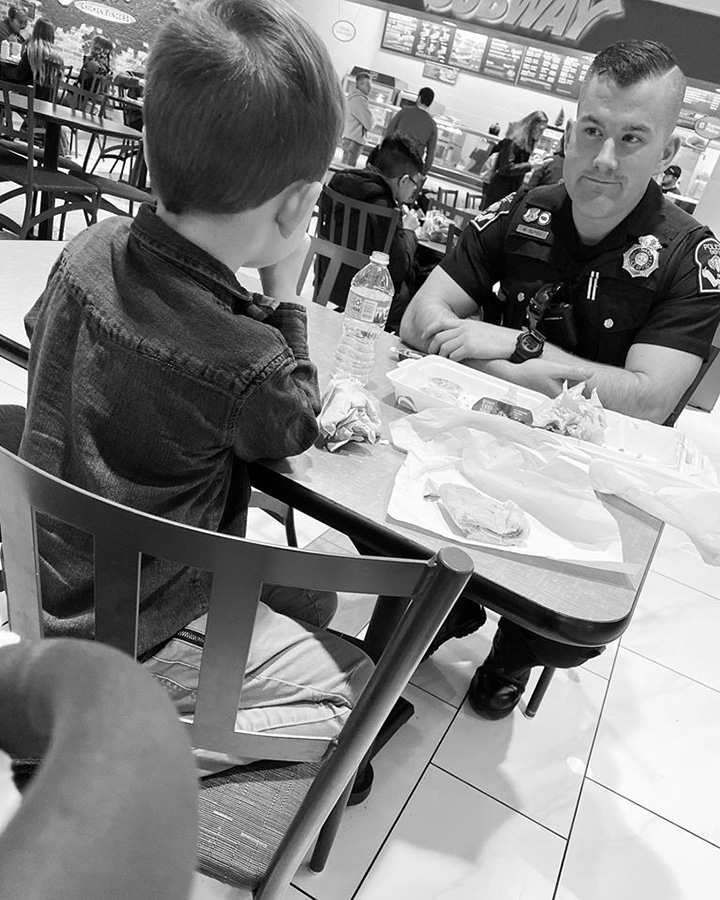 boy quits playing to eat with cop sitting alone