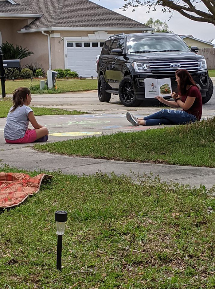 teacher reads to students in driveway