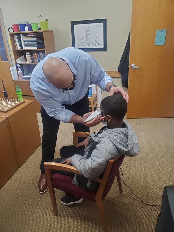 principal helps student hair cut