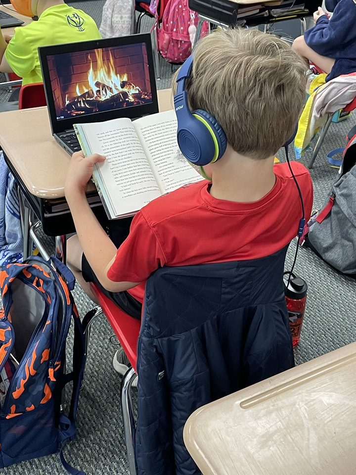 student reading with fireplace on ipad