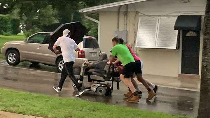 boys push woman in wheelchair in the rain