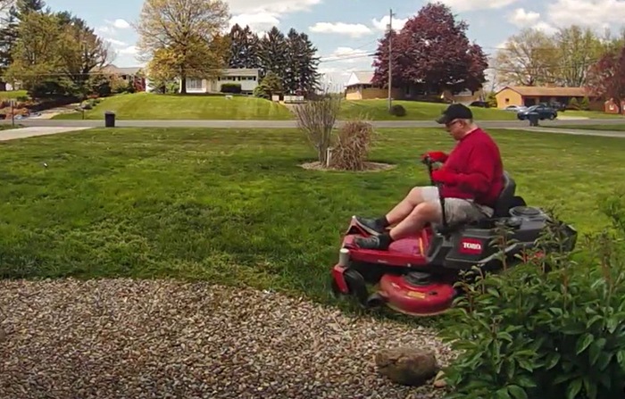 man cuts grass for woman